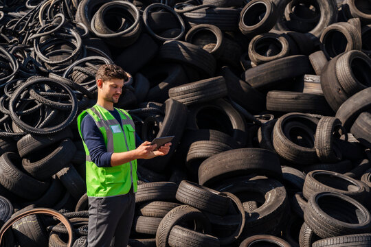 Man using tablet PC in front of rubber tires at recycling center