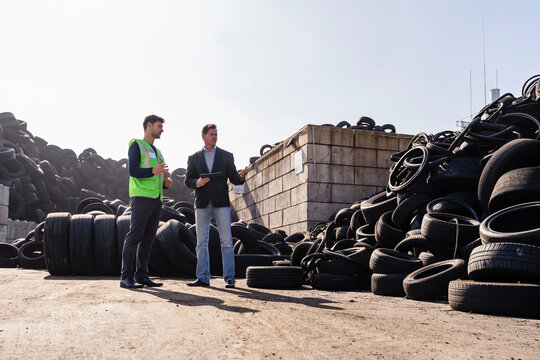 Mature businessman discussing over rubber tires with colleague - Powered by Adobe