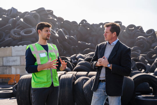 Businessman with colleague having discussion in front of tires