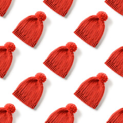 Seamless pattern of handmade red knitted hat with pompom for winter season isolated on white background.