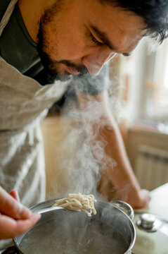 Man examining hot soup in kitchen at home