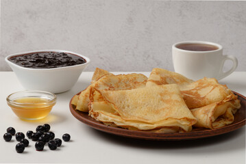 Pancakes with jam, honey and a tea on a table