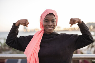 Portrait of a young african woman wearing a pink headscarf for cancer standing strong