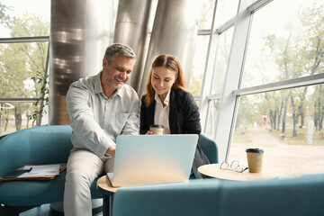Man and woman are looking through material for new project in laptop