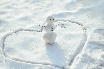 Little snowman stand in a heart. Winter
