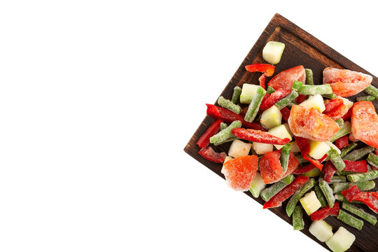 Fresh Frozen vegetables, tomatoes, string beans, zucchini, red pepper on wooden cutting board, top view. White background, copy space