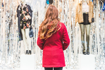 Rear view of young woman wearing a red coat shopping in the city