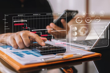Investors working using calculator to calculate with smartphone, laptop the tax of static in...