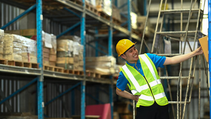 Asian male worker suffering from back pain while sitting on stairs in warehouse. Industrial and industrial workers concept