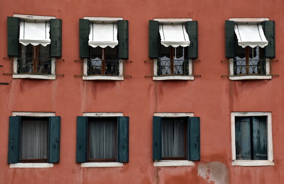 Fenster in einer roten Hausfassade in Venedig