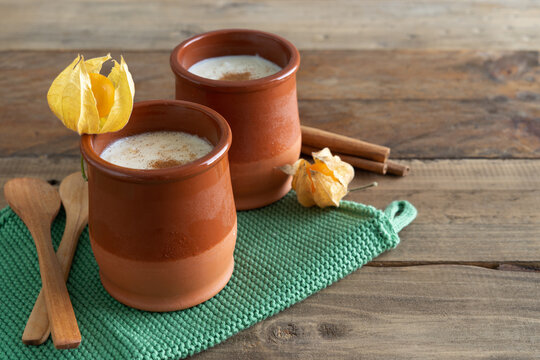 Bowls of rice pudding and cinnamon on a wooden background. Copy space.