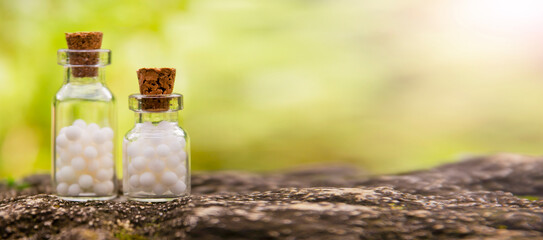 Homeopathic balls in bottles on the background of nature. Homeopathy alternative medicine concept.