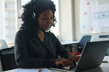 African american woman in a mobile headset works on computer