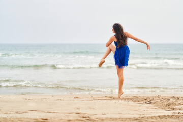 Fototapeta na wymiar a dancer in a blue dress on the beach performing contemporary modern dance