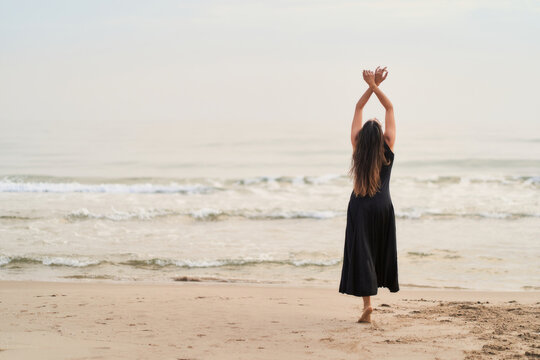 a dancer in a black dress on the beach expressing strength and courage in her movements
