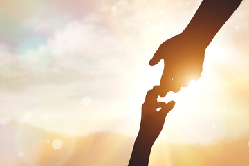 silhouette of two hands on sunset background, help concept, hope and mutual support, peace thanks...