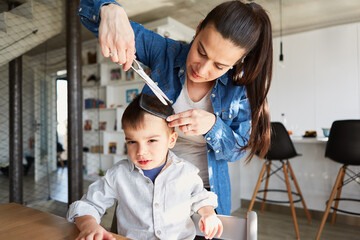 Mutter oder Friseurin beim Haare schneiden von Junge