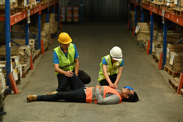 Warehouse workers are helping and giving the injured first aid to colleague lying unconscious on concrete floor