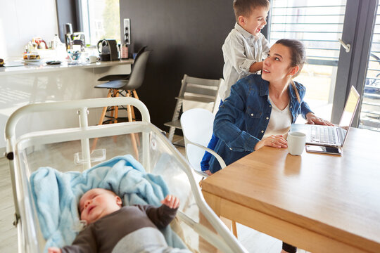 Gestresste Mutter im Home Office mit Baby und Sohn