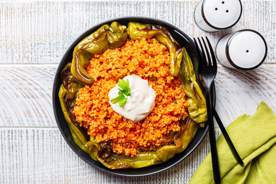Tomato bulgur pilaf with onion and baked green peppers,  natural yoghurt. Turkish dish. Top view.