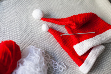 Santa hat handmade crochet. Crocheting Santa hats  of red and white yarn at home as hobby and leisure activity. Two hats as Christmas gifts. Crocheting tutorials.