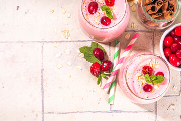 Healthy winter Christmas drink, cranberry oatmeal smoothie of yogurt, with fresh cranberries on beige tiled table, copy space