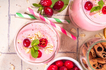 Healthy winter Christmas drink, cranberry oatmeal smoothie of yogurt, with fresh cranberries on beige tiled table, copy space
