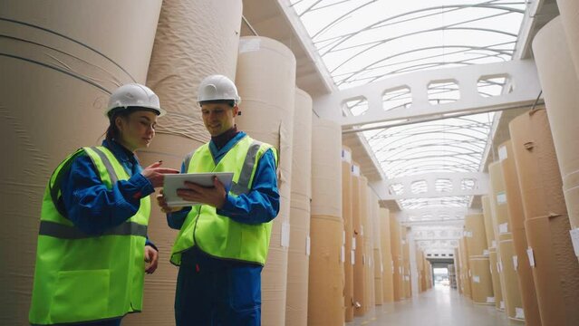 Warehouse of a paper factory. Rolls of paper, engineers enter data into a tablet