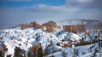 winter landscape of bryce canyon national park; freezing cold red rocks covered with snow, winter...