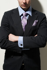 Cropped close-up shot of a man in a black pinstripe suit, a blue shirt with a purple printed tie...