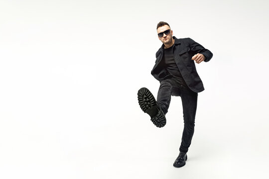 Guy showing beast, stepping on camera, shoe sole close up. Full length portrait man fashion model who steps on the camera. Fashion concept. Emotions. White background.