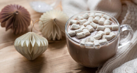 Stylish paper Christmas tree toys and a glass with hot chocolate, marshmallows on a wooden background. Beige tones. View from above. Banner for design, web pages.