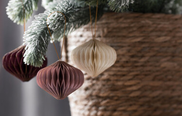 Stylish paper Christmas tree toys in Scandinavian style on fir branches. Beige tones. Banner for design, web pages. The concept of a stylish new year and Christmas 2023.