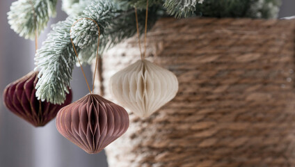 Stylish paper Christmas tree toys in Scandinavian style on fir branches. Beige tones. Banner for...