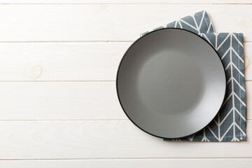 Top view on colored background empty round gray plate on tablecloth for food. Empty dish on napkin...