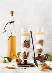 Two glasses with cold layered  dessert. Chocolate and yoghurt cream, granola and medlar liquor. Homemade sweet food concept. (Mespilus germanica)