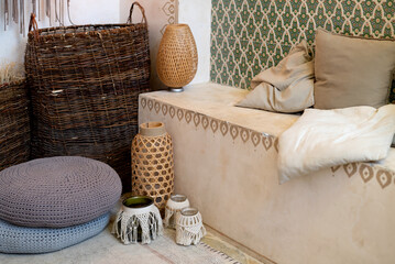 Middle east interior details in beige colors with boho decoration, cushions on couch near wall with ornate pattern