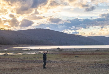 Man taking a selfie with his phone on a waters age lake mountain landscape