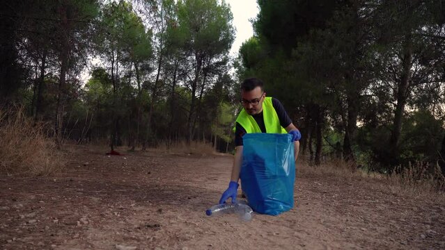 Guardabosque recogiendo pl&aacute;stico en la monta&ntilde;a. Video horizontal 4K. 