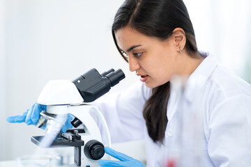 Female scientist working in medical biotechnology research laboratory using microscope for advanced chemistry analyzing. Doctor woman experiment vaccine innovation in microbiology development lab.