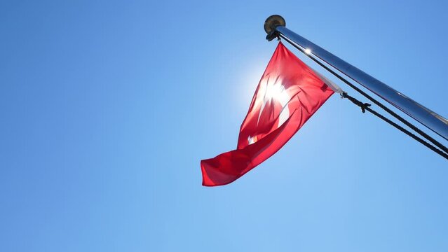Flag of Turkey flutter on wind, bright sun light flash, shine through fabric. Red ensign at ferry boat of Bosporus, shot in sunny summer day, clear blue sky on background