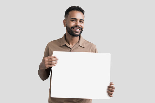 Young man holding blank white board for advertise text isolated on gray background