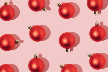 Holiday greeting pattern with red baubles on pink background. Minimal concept.