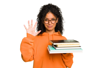 Young student woman holding a pile of books isolated smiling cheerful showing number five with fingers.