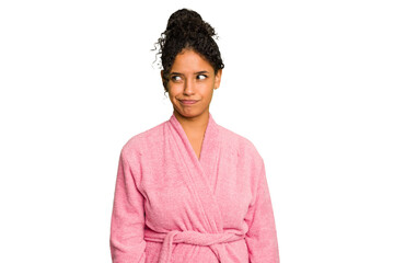 Young brazilian woman wearing a pink bathrobe isolated confused, feels doubtful and unsure.
