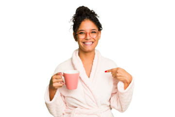 Young brazilian woman wearing a pajama holding a cup isolated person pointing by hand to a shirt copy space, proud and confident