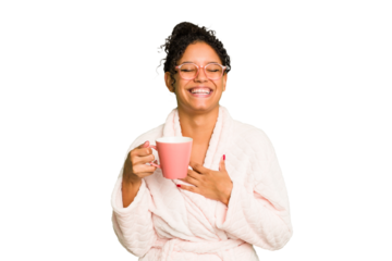 Young brazilian woman wearing a pajama holding a cup isolated laughs out loudly keeping hand on chest.