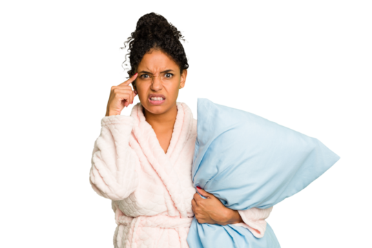 Young brazilian woman wearing a pajama holding a pillow isolated showing a disappointment gesture with forefinger.