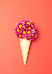 Daisy flowers in ice cream cone on pastel red background. Minimal summer flat lay composition.