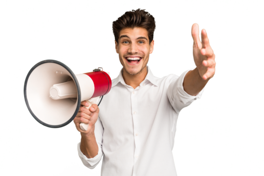 Young caucasian man holding megaphone isolated receiving a pleasant surprise, excited and raising hands.